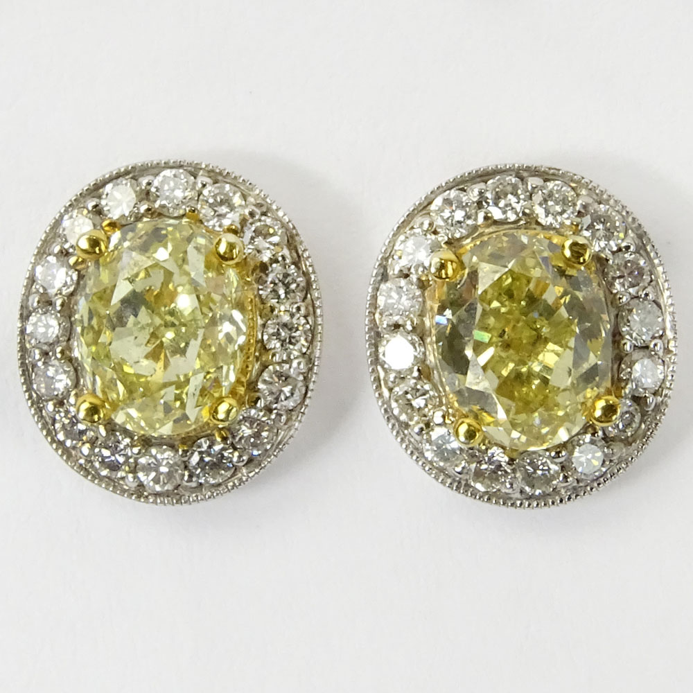 Pair of Approx. 2.05 Carat Oval Cut Fancy Yellow Diamond, .50 Carat Round Cut Diamond, 14 Karat White Gold and 18 Karat Yellow Gold Earrings. 