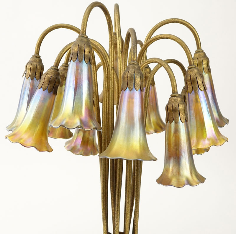 Important Tiffany Studios Twelve-Light Pond Lily Lamp. The pond lily base of dore bronze, the drop cluster blossom design shades in iridescent favrile glass. 
