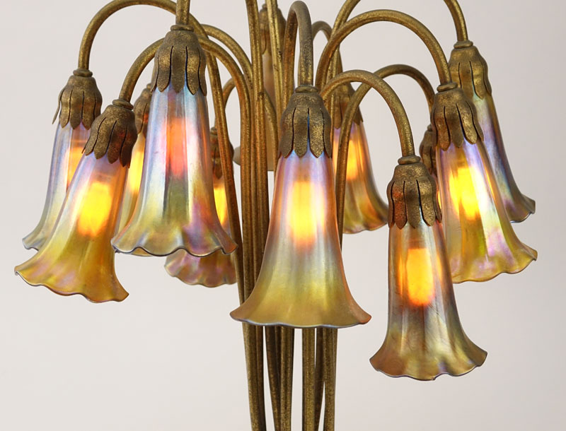 Important Tiffany Studios Twelve-Light Pond Lily Lamp. The pond lily base of dore bronze, the drop cluster blossom design shades in iridescent favrile glass. 