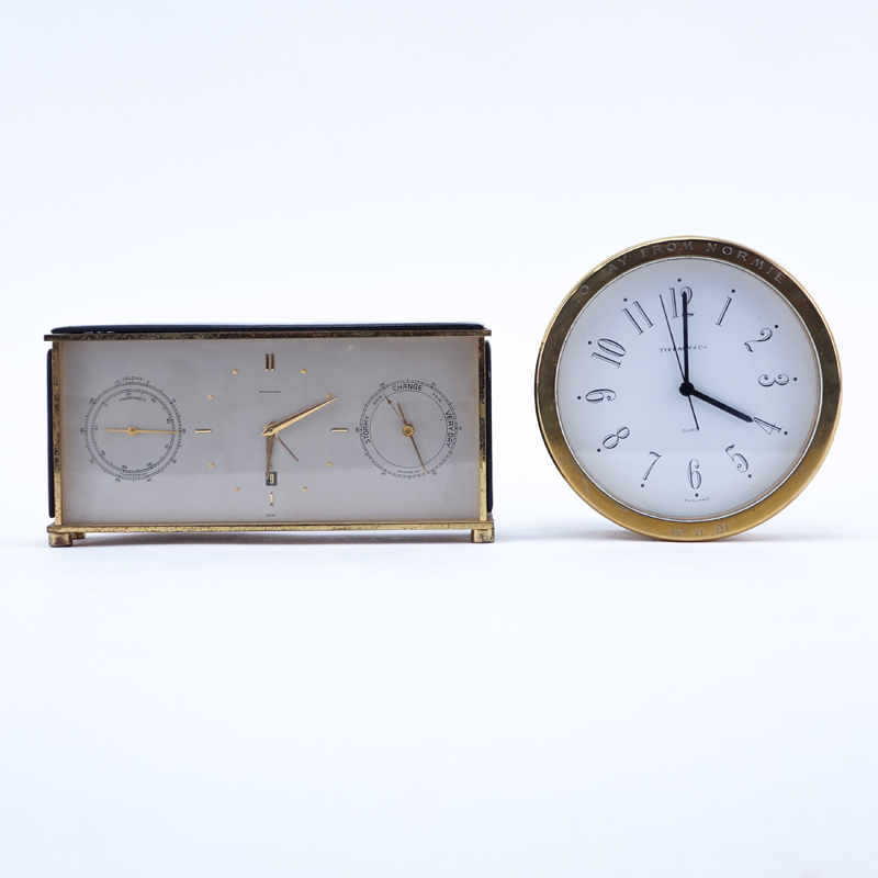 Two Brass Clocks. A Tiffany & Co. round quartz clock, inscribed "To Jay From Normie 12-11-81"; a Saks brass and leather Swiss desk clock with temperature and barometer. 