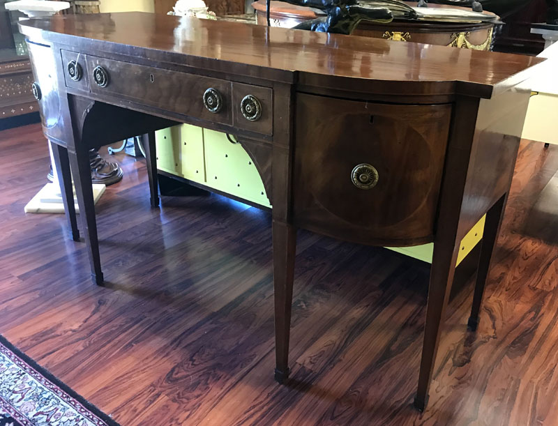 Antique Sheraton Flame Mahogany Sideboard. Center has fitted wide drawer, a pair of sliding doors, large deep drawers and large sliding drawer all with brass pulls, stands on high tapering legs, missing key.