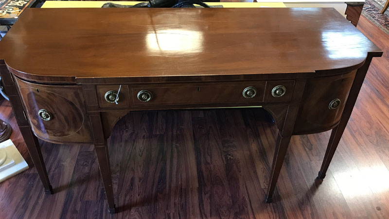 Antique Sheraton Flame Mahogany Sideboard. Center has fitted wide drawer, a pair of sliding doors, large deep drawers and large sliding drawer all with brass pulls, stands on high tapering legs, missing key.