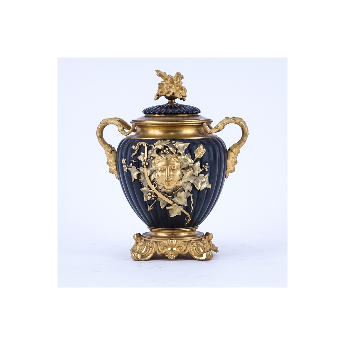 Neoclassical Style Gilt Brass and Painted Covered Urn with Bacchus Motif. Light rubbing to gilt overall good condition.