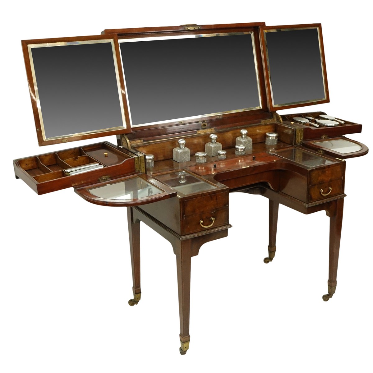 Attributed to: George Betjeman & Sons Circa 1910 Edwardian Mahogany Enclosed Dressing Table. The rectangular hinged top enclosing an interior fitted with three beveled mirror plates, above two hinged compartments flanked by two glass slides and a recessed