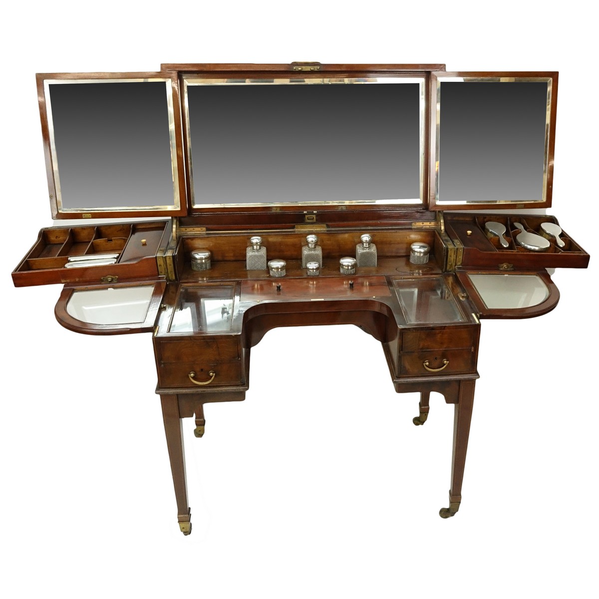 Attributed to: George Betjeman & Sons Circa 1910 Edwardian Mahogany Enclosed Dressing Table. The rectangular hinged top enclosing an interior fitted with three beveled mirror plates, above two hinged compartments flanked by two glass slides and a recessed