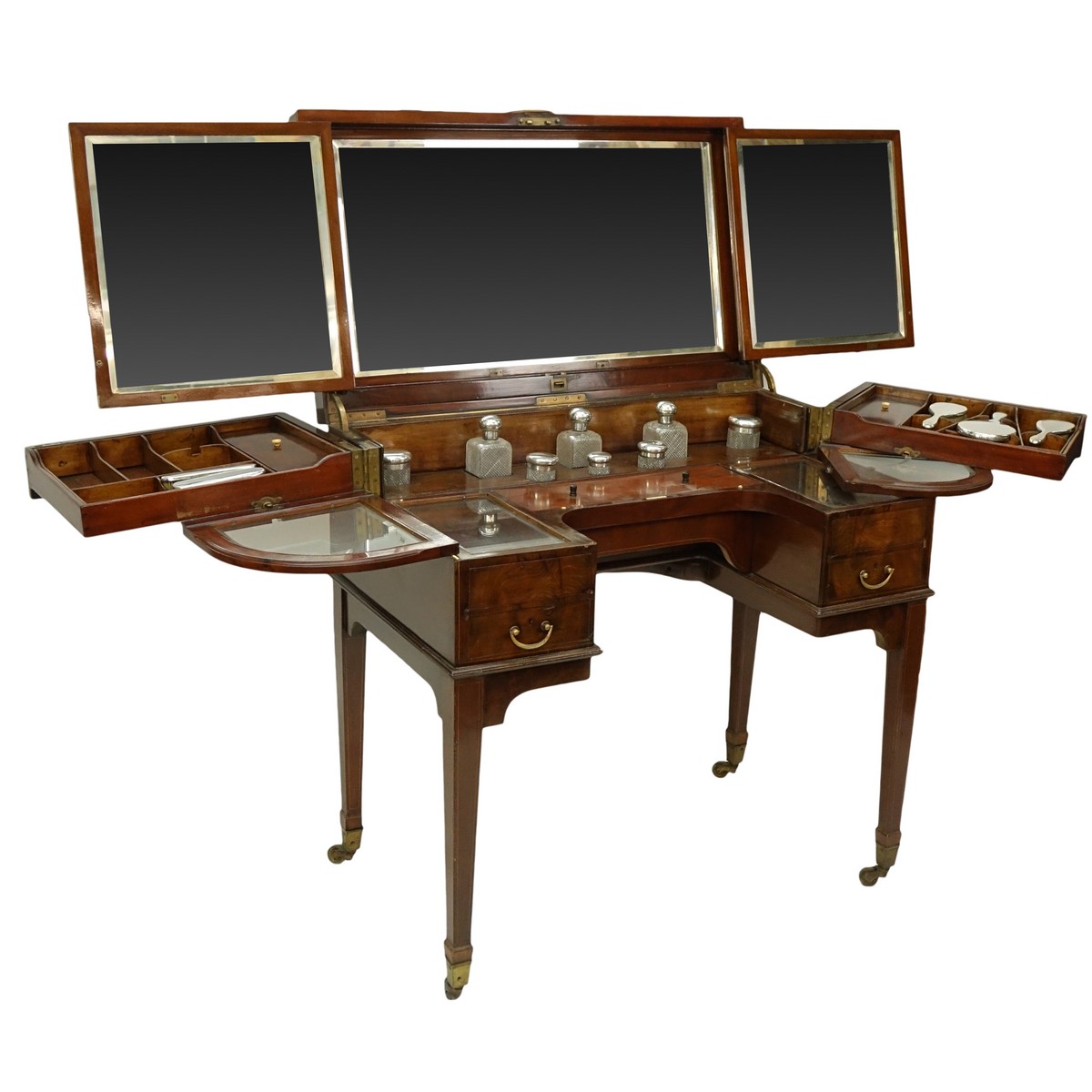 Attributed to: George Betjeman & Sons Circa 1910 Edwardian Mahogany Enclosed Dressing Table. The rectangular hinged top enclosing an interior fitted with three beveled mirror plates, above two hinged compartments flanked by two glass slides and a recessed