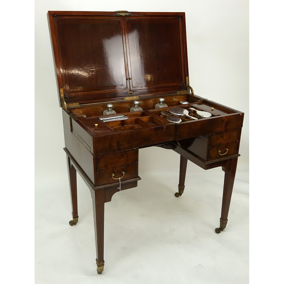 Attributed to: George Betjeman & Sons Circa 1910 Edwardian Mahogany Enclosed Dressing Table. The rectangular hinged top enclosing an interior fitted with three beveled mirror plates, above two hinged compartments flanked by two glass slides and a recessed