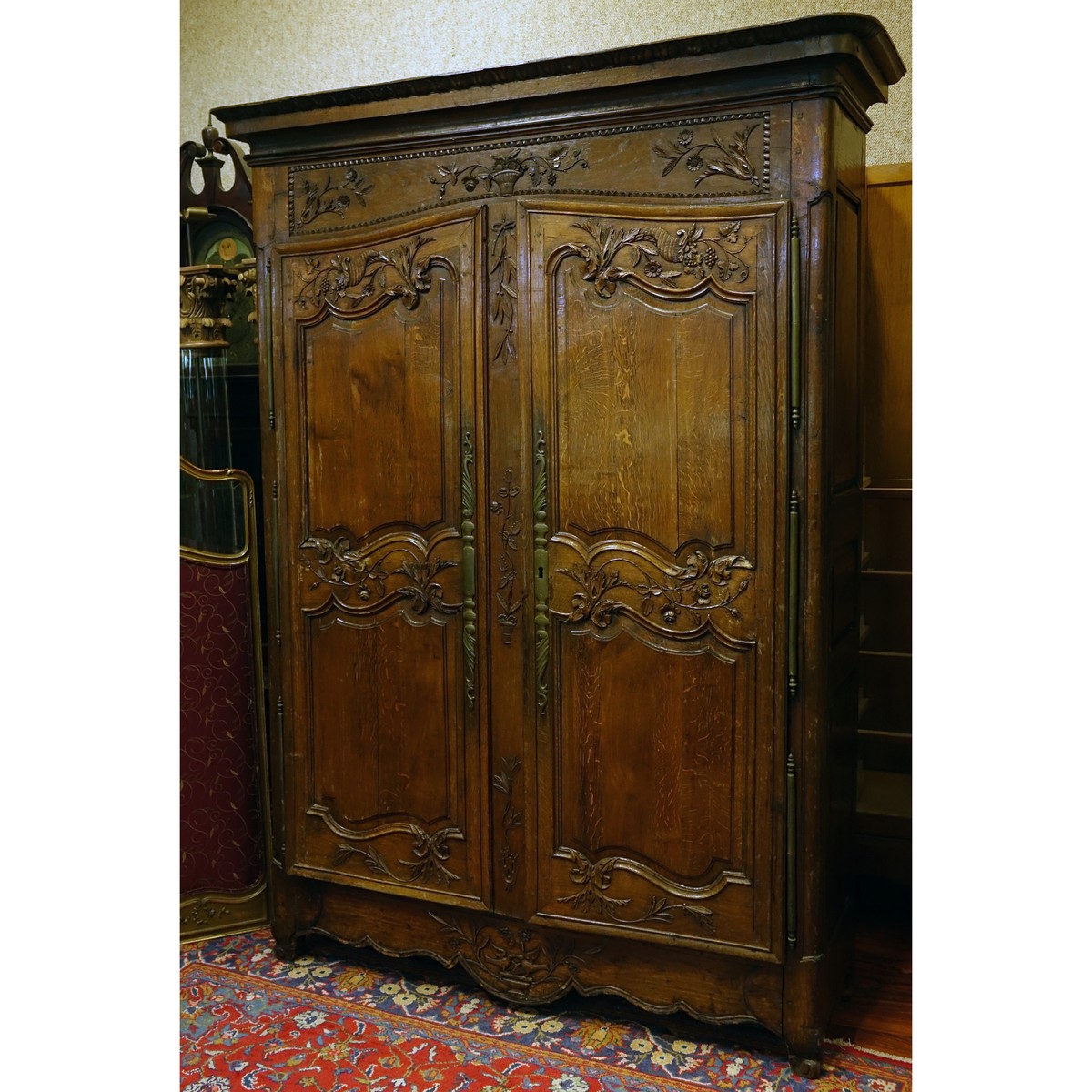 Early 19th Century Louis XV Style Carved Oak Armoire with Bronze Mounts. Carved with baskets, urns, flowers and leaf work throughout the surface.