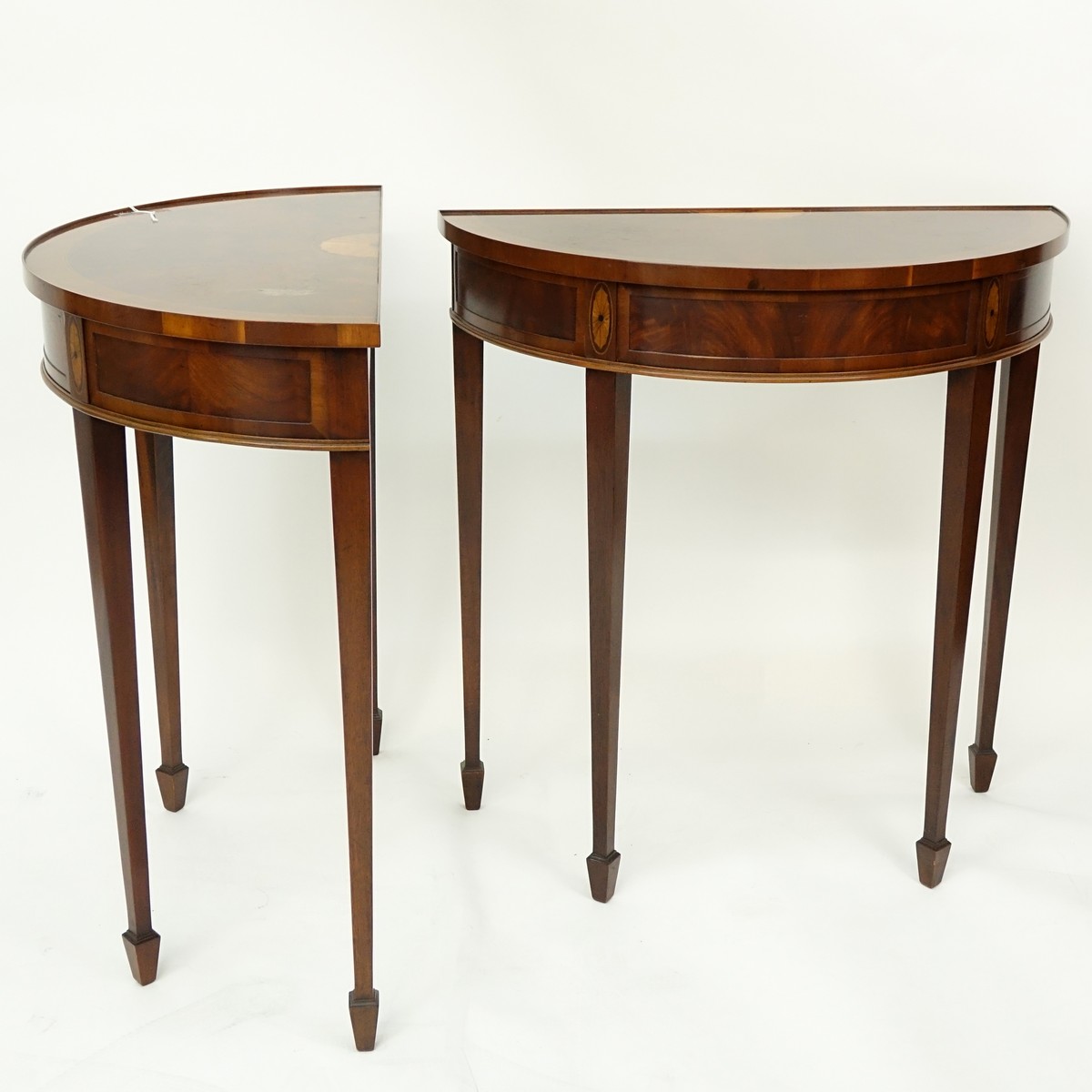 Pair of Sheraton Style Flame Mahogany, Marquetry Inlaid Demi Lune Tables. Light scuffs to top on both, one has wear to veneered top.