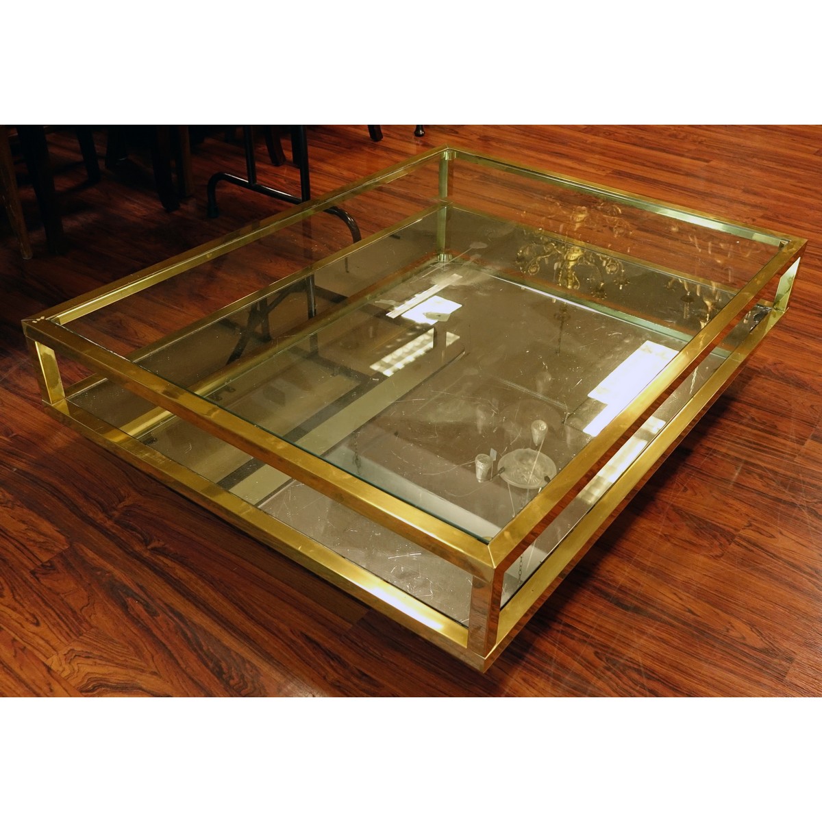 Mid Century Modern Mirrored and Glass Top Coffee Table. Scratches to brass, scratches to glass top, and mirror has a loss to corner.