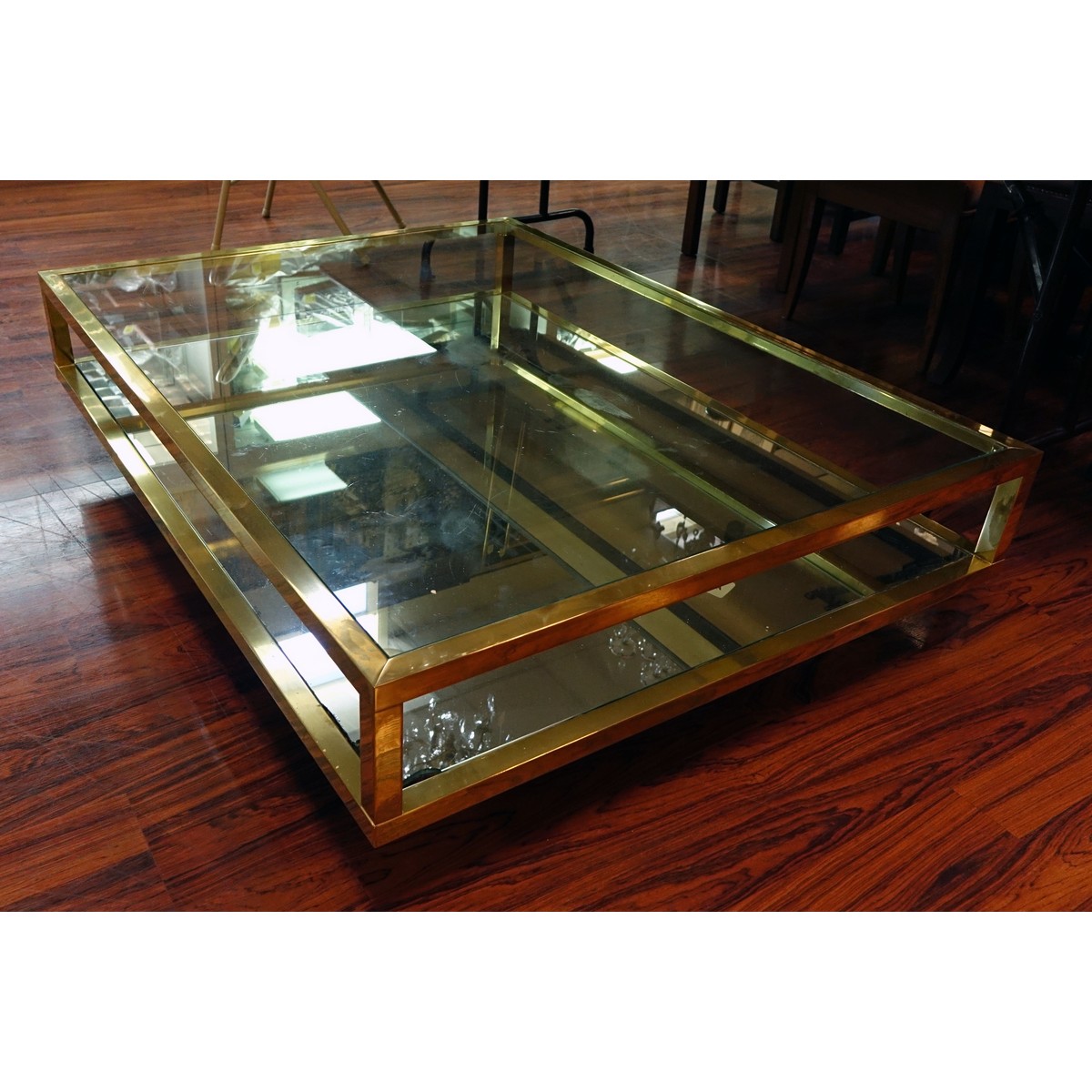 Mid Century Modern Mirrored and Glass Top Coffee Table. Scratches to brass, scratches to glass top, and mirror has a loss to corner.