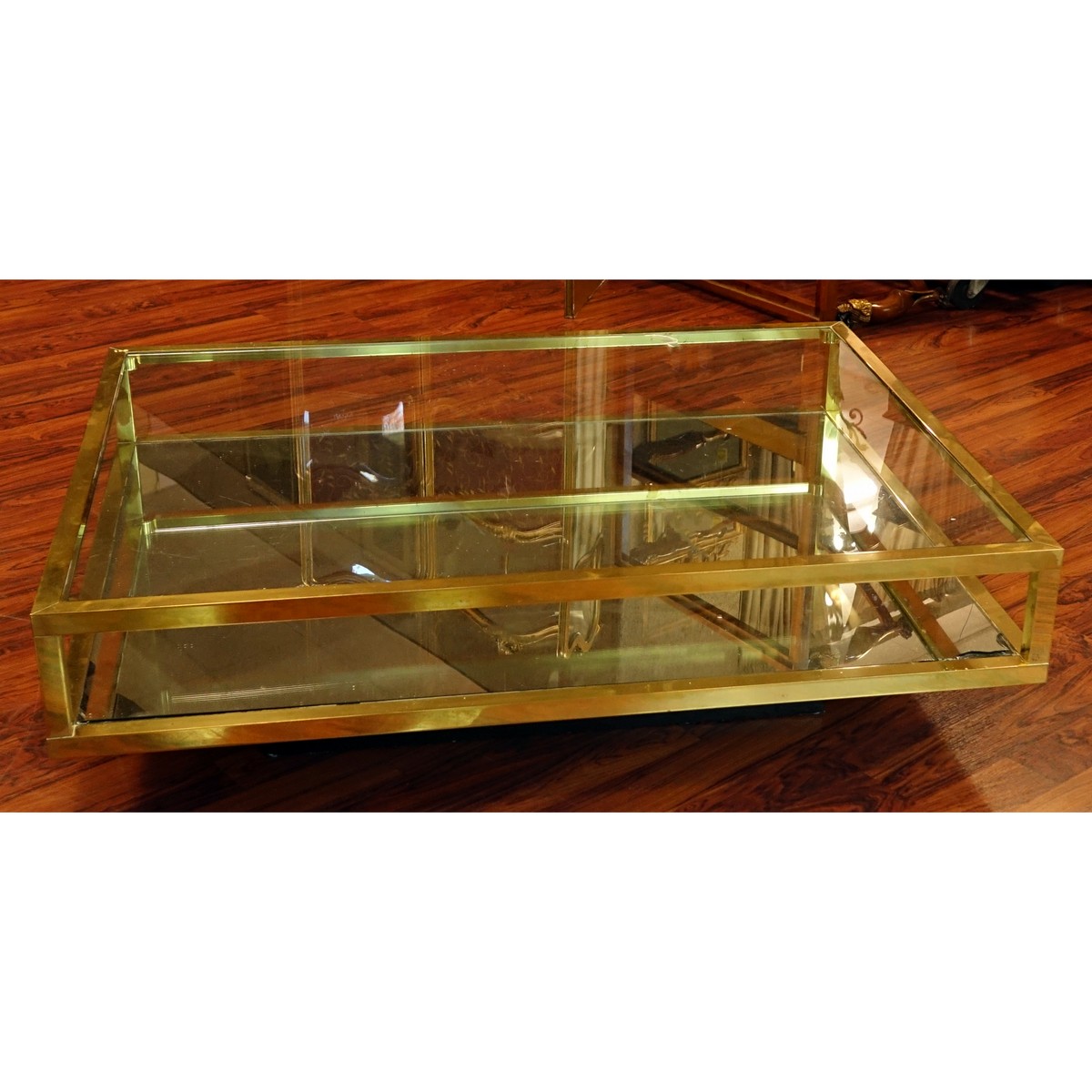 Mid Century Modern Mirrored and Glass Top Coffee Table. Scratches to brass, scratches to glass top, and mirror has a loss to corner.