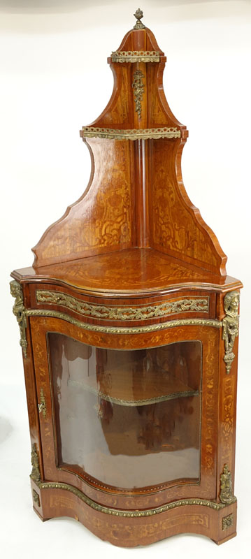 20th Century Louis XVI Style Mahogany Floral Inlaid, Bronze Mounted Corner Cabinet. Serpentine form with single fitted drawer and glass door, gallerie gate to top and interior shelves, figural mounts flaking the corners.