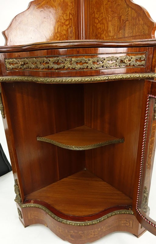 20th Century Louis XVI Style Mahogany Floral Inlaid, Bronze Mounted Corner Cabinet. Serpentine form with single fitted drawer and glass door, gallerie gate to top and interior shelves, figural mounts flaking the corners.