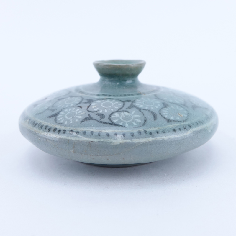 Chinese Goryeo Dynasty, 12th - 14th Century Celadon Glazed Oil Bottle. With a broad flat shoulder, inlaid in black and white slip with a band of chrysanthemum scrolls between dotted lines.