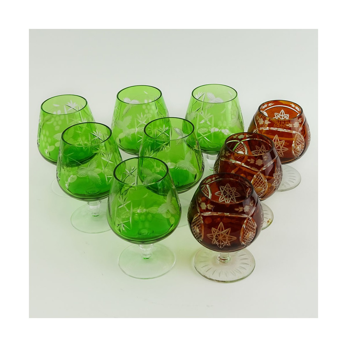 Lot of 9 Bohemian Cut Glass Brandy glasses in Green and Deep Orange. Various stems. Measure 4-1/2" 