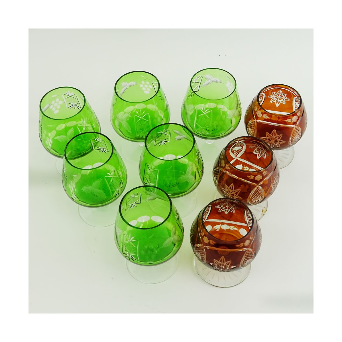 Lot of 9 Bohemian Cut Glass Brandy glasses in Green and Deep Orange. Various stems. Measure 4-1/2" 