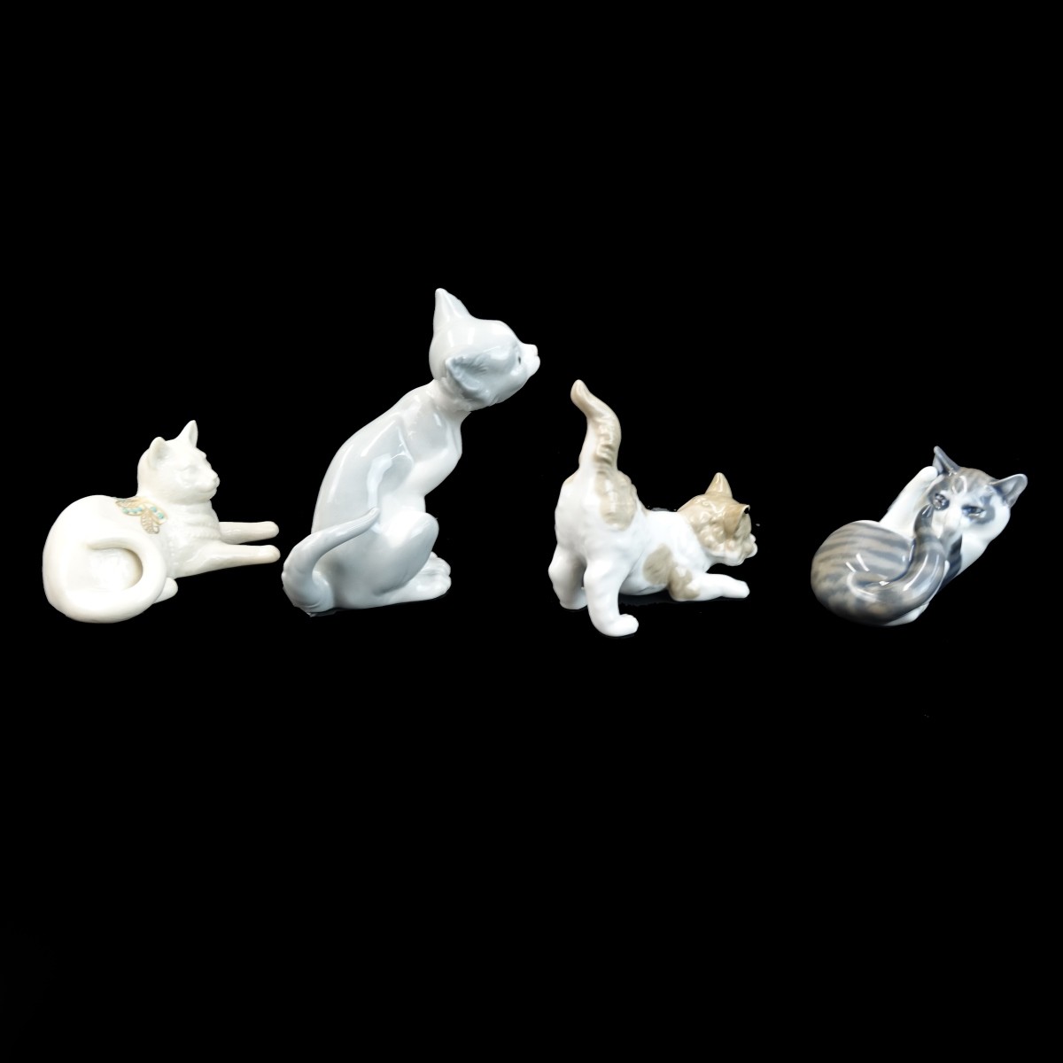 Four Playful Porcelain Cat Figurines